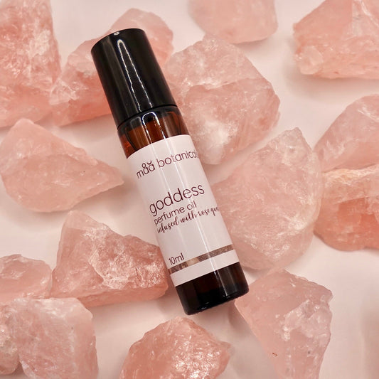 Bottle of maa botanicals goddess perfume oil on rose quartz crystals