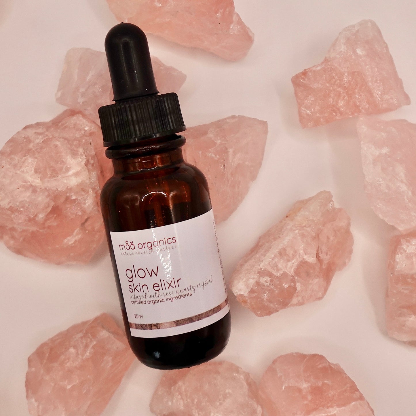 glow skin elixir bottle surrounded by rose quartz crystals