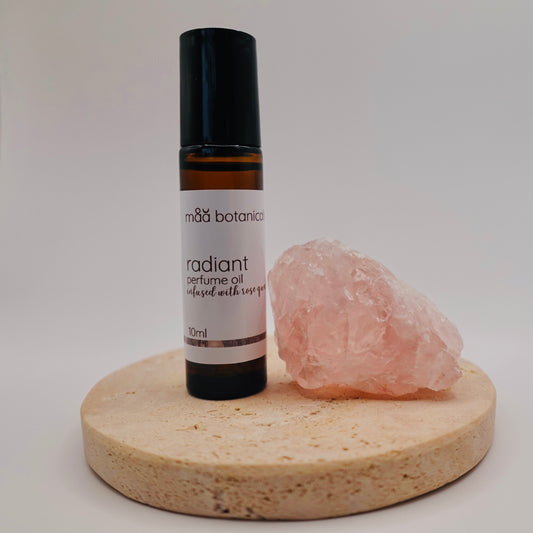Radiant perfume oil bottle with a rose quartz crystal on a stone stand
