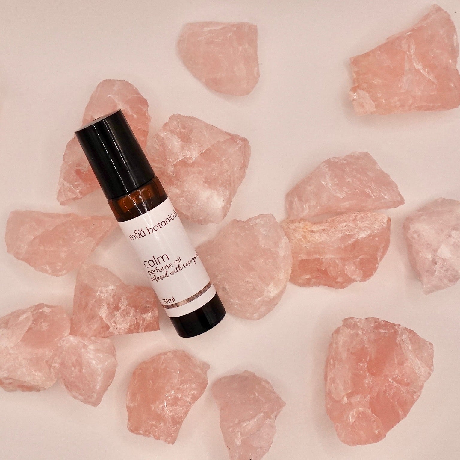 maa botanicals calm perfume oil surrounded by rose quartz crystals 