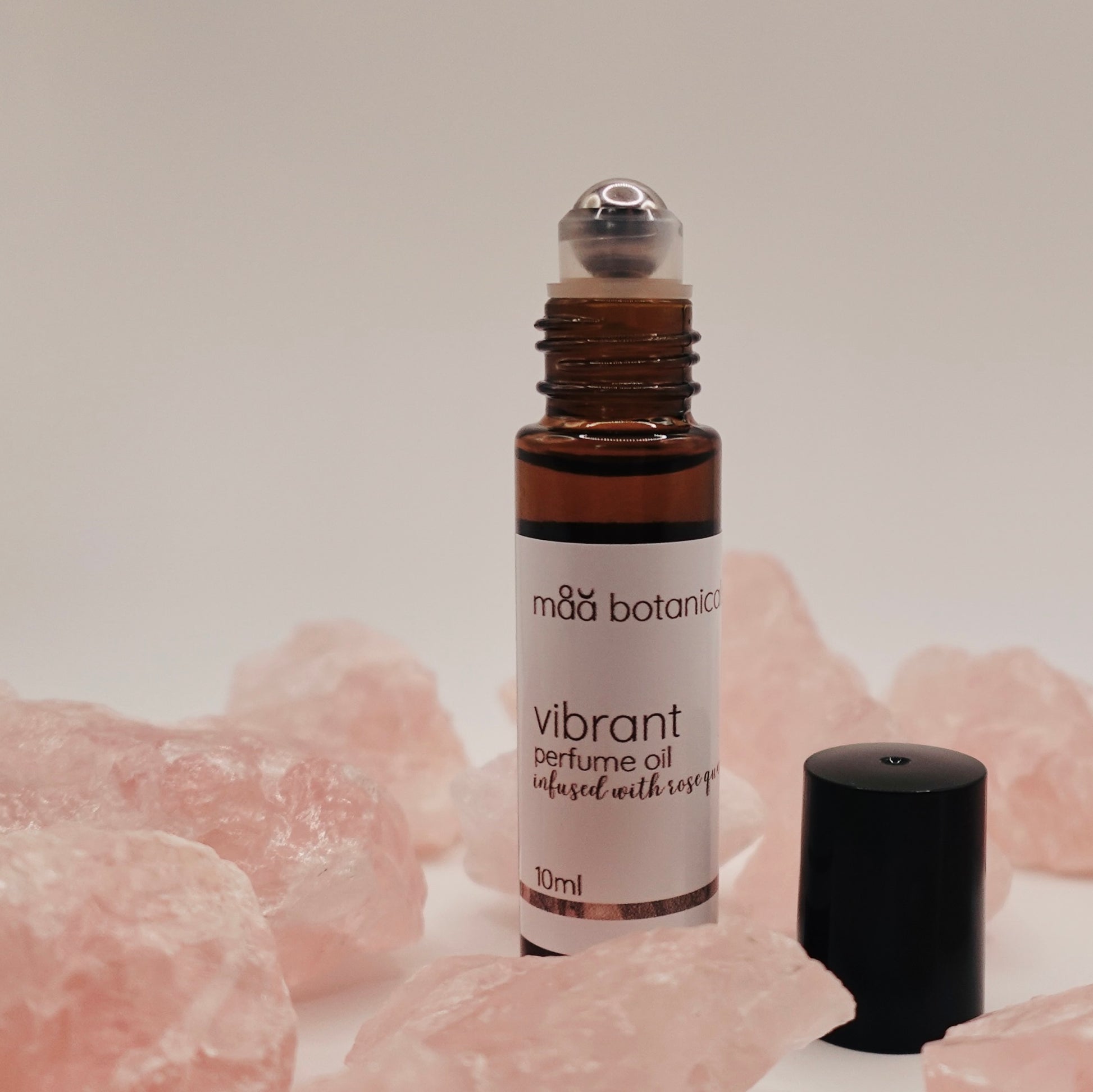 Roll-on bottle of mäa botanicals vibrant perfume oil with rose quartz crystals 