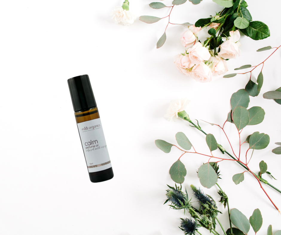 aromatherapy perfume bottle labeled 'calm' with flowers and greenery on a white background