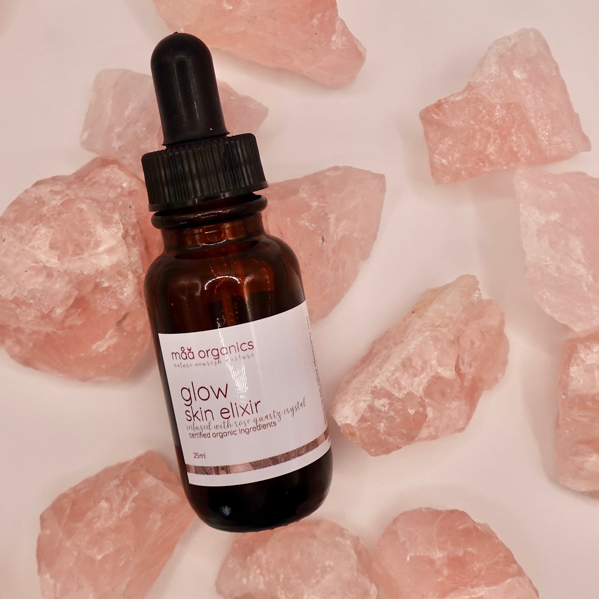 glow skin elixir bottle surrounded by rose quartz crystals