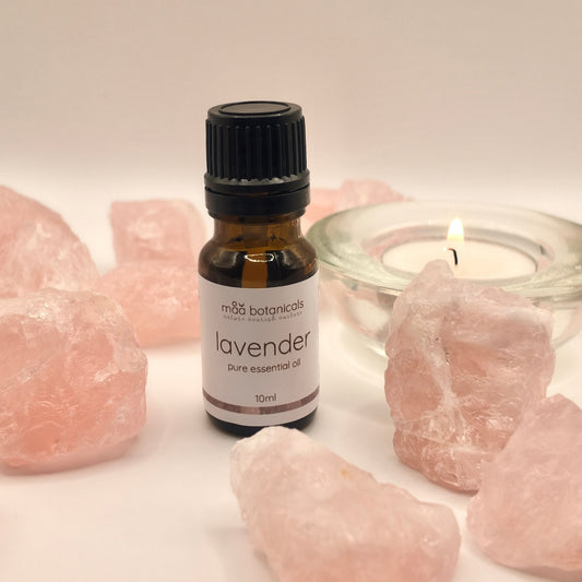 lavender essential oil in a 10ml amber bottle surrounded by rose quartz crystal and a tealigt candle