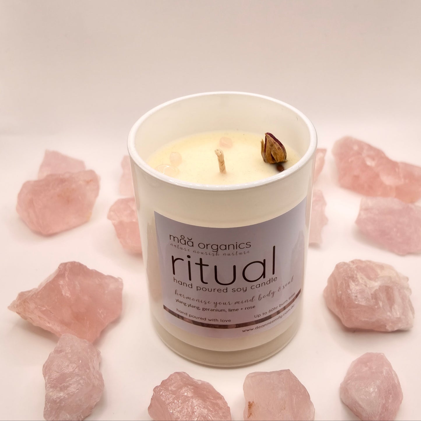 maa botanicals candle in a white opaque jar surrounded by rose quartz crystals