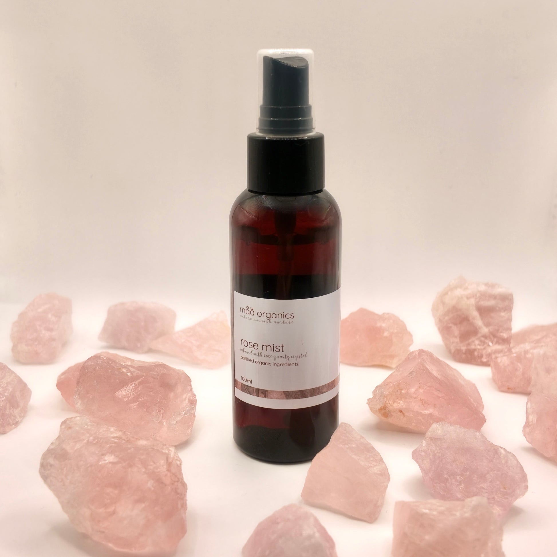 maa botanicals rose mist in a 100ml amber bottle with mist spray surrounded by rose quartz crystal