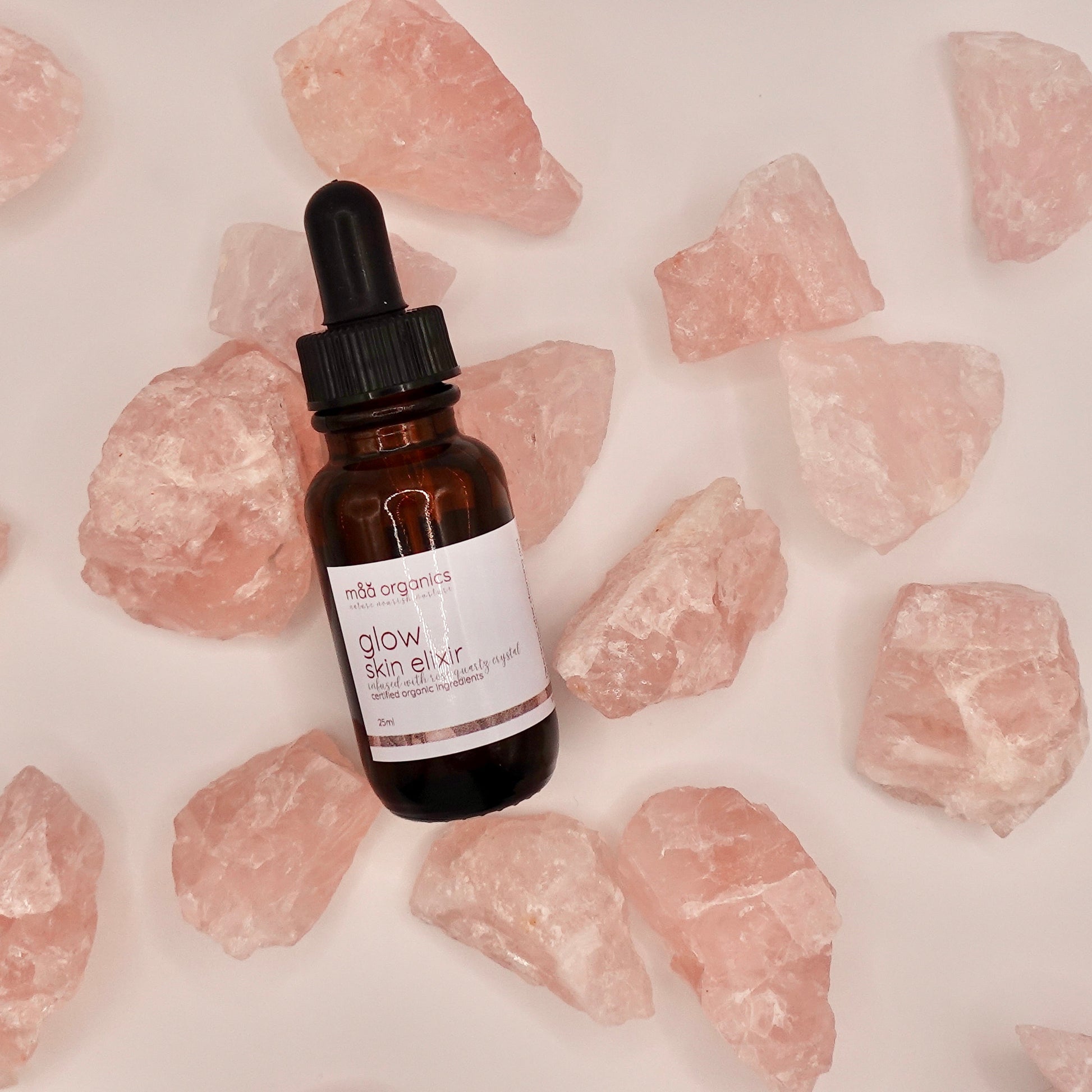 glow skin elixir bottle surrounded by rose quartz crystals