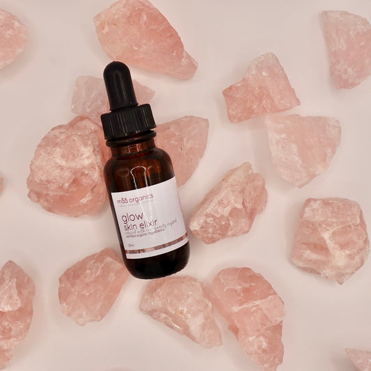 glow skin elixir bottle surrounded by rose quartz crystals